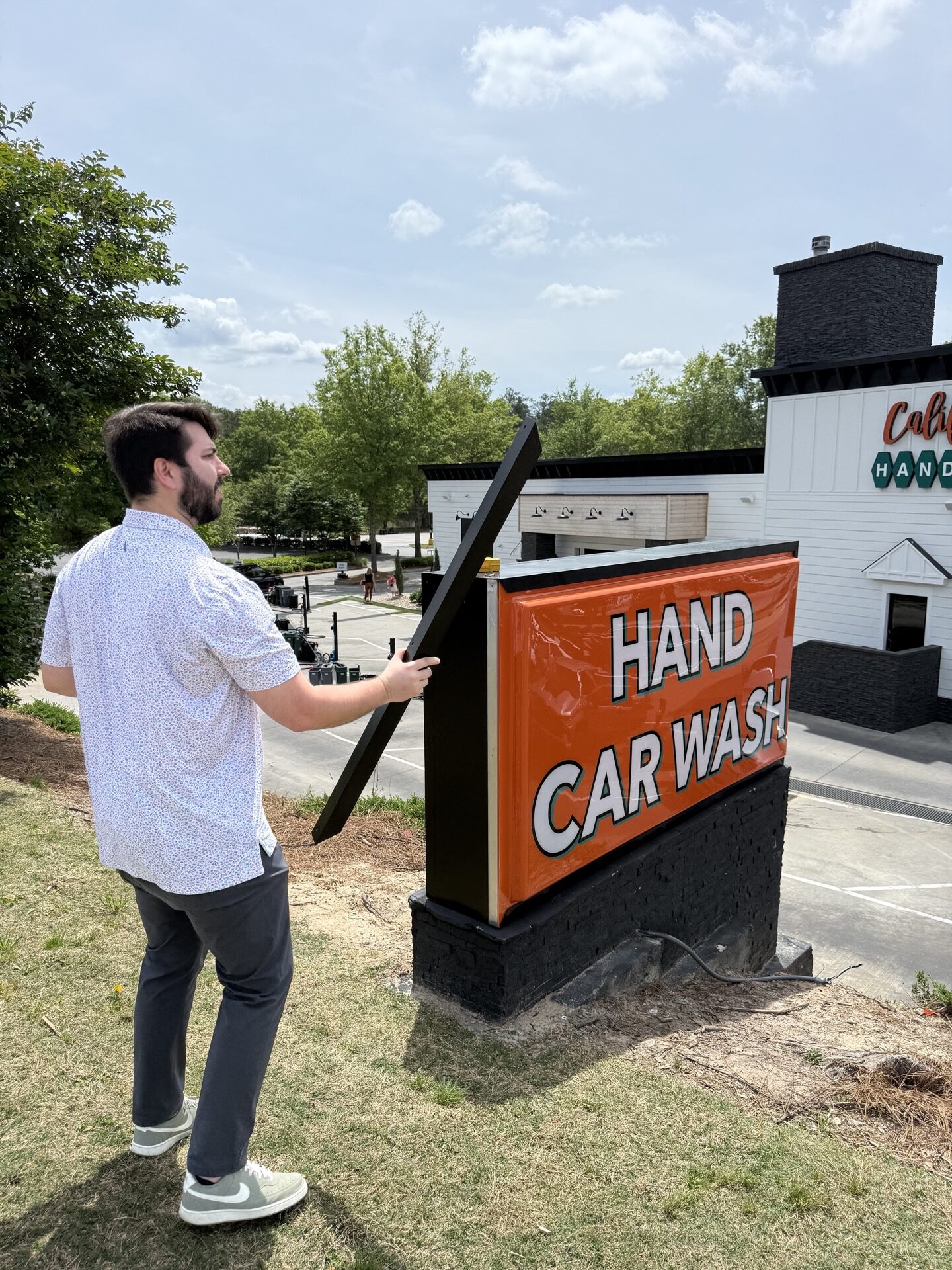 Christian Tardif installing a monument sign at California Hand Wash, positioning the structure near the edge of the property for maximum visibility.