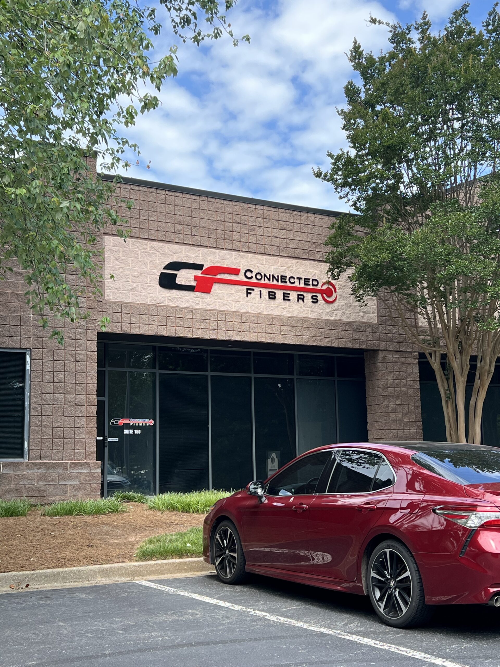 Laser-cut acrylic sign reading 'Connected Fibers,' featuring 1/2-inch thick painted letters pin mounted to an exterior wall in Roswell, GA.